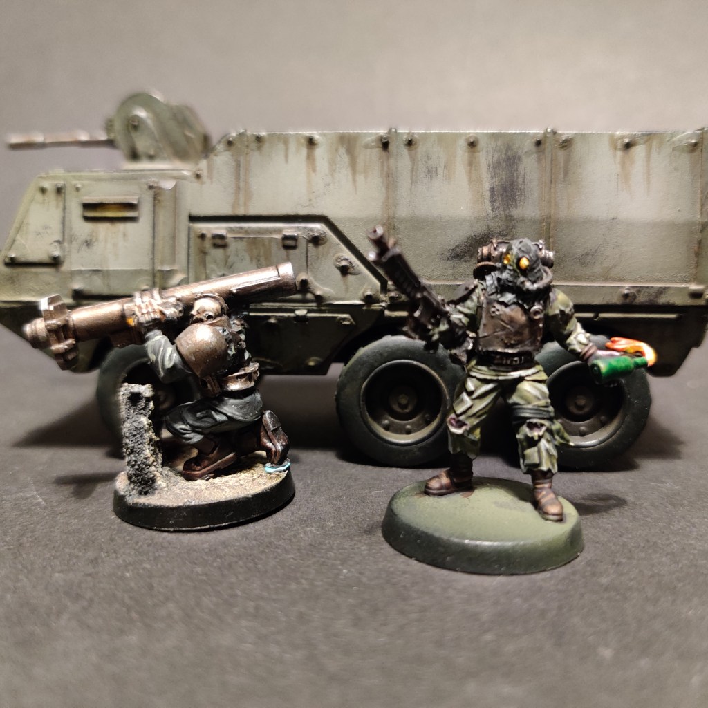Two warhammer 40k renegade guardsmen in front of a troop truck